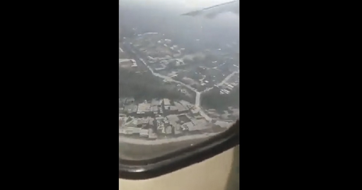 A view out a plane window shows the ground is close.