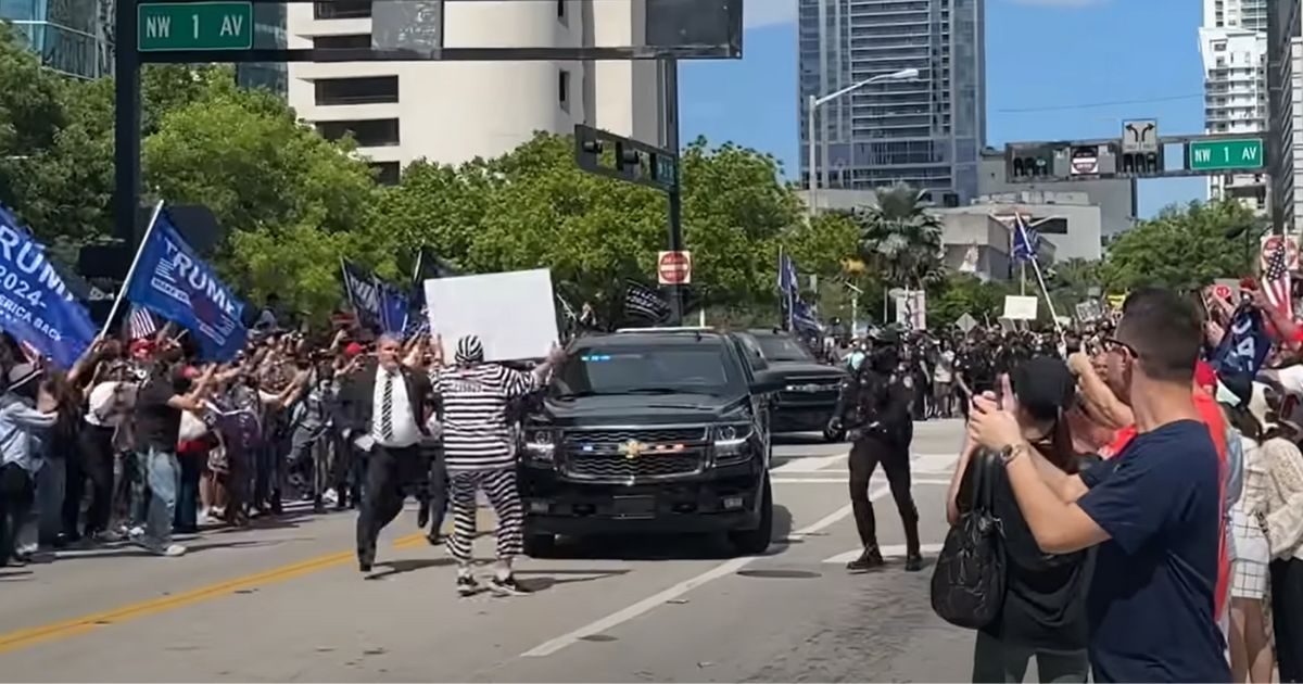 Anti-Trump demonstrator Dominic Santana walks in front of Trump's motorcade in Miami, Florida, on Tuesday.