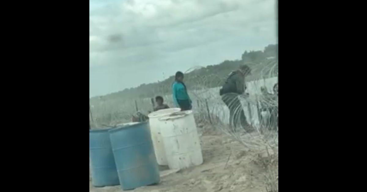 A U.S. Border Patrol officer cuts razor wire on the Texas side of the Rio Grande to allow illegal immigrants to come on shore.